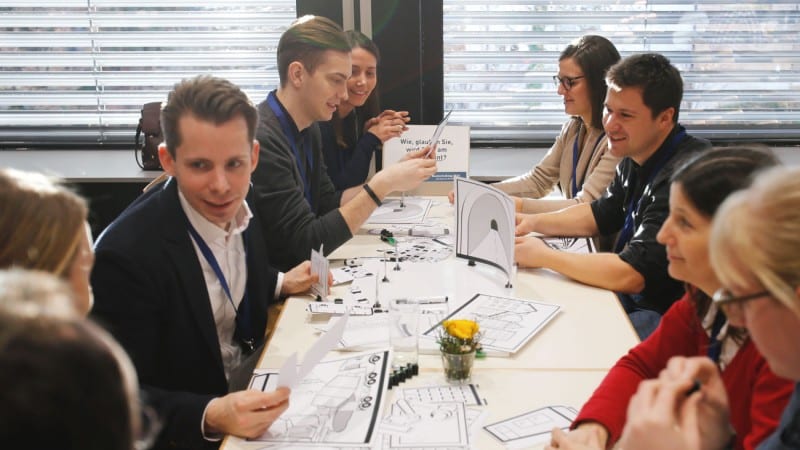 Gruppe von elegant gekleideten Menschen unterhalten sich beim gemeinsamen Essen