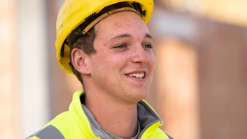 Portrait of a young man wearing a construction helmet and a bright yellow jacket