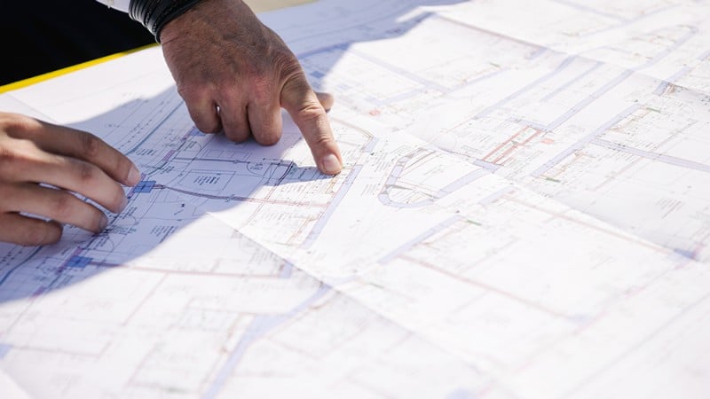 Hands point to a construction plan