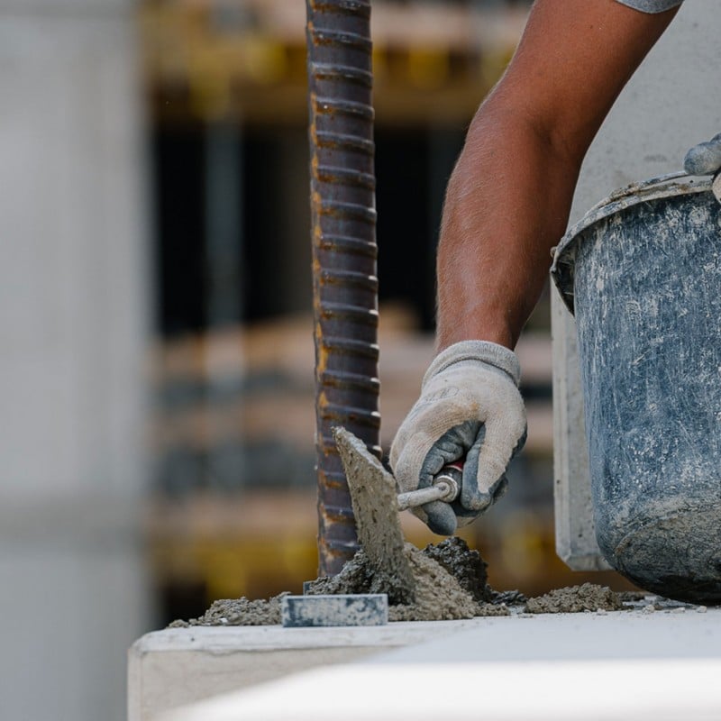 Close-up of hands and a bucket during plastering work